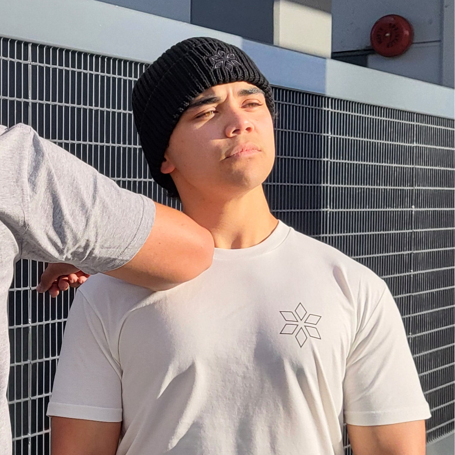 Teenage boy wearing black beanie with black embroidered HUA star on front