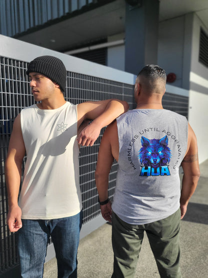 Two men standing outdoors next to a metal fence, showcasing sleeveless tank tops. The man on the left wears a cream tank top with a small black star logo on the chest, paired with a black beanie.